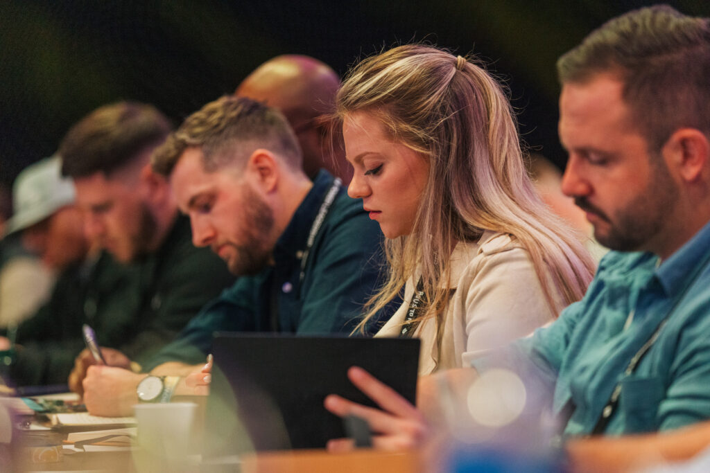 woman takes notes during presentation at conference 